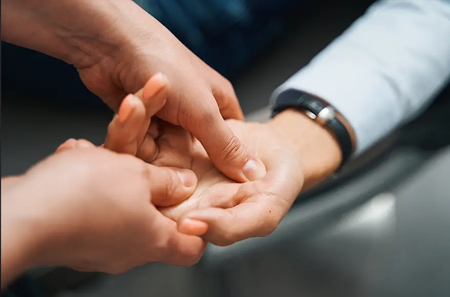 TraumaSolutions Close-up of one person pressing the palm of another person’s hand, possibly demonstrating a massage technique or an EFT (Emotional Freedom Techniques) practice often used in trauma therapy for deeper healing.