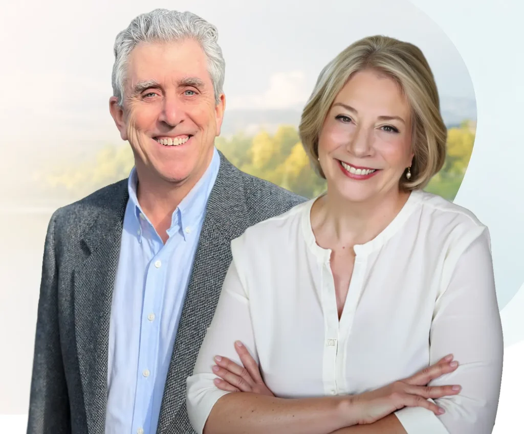 TraumaSolutions Two adults, one man in a gray blazer and blue shirt, and one woman in a white top, stand smiling in front of an outdoor background, embodying the positive transformation that can come from trauma therapy and deeper healing.