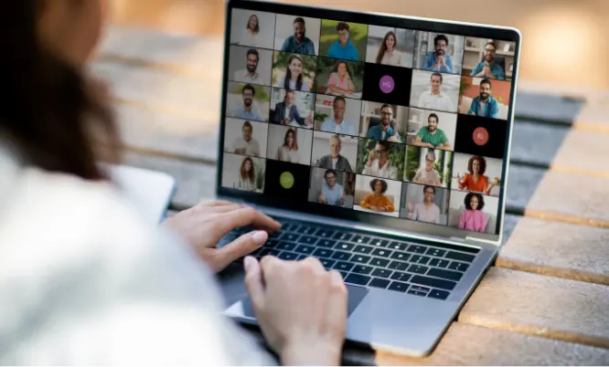 TraumaSolutions A person using a laptop participates in a video conference call with many people, each shown in individual boxes on the screen.