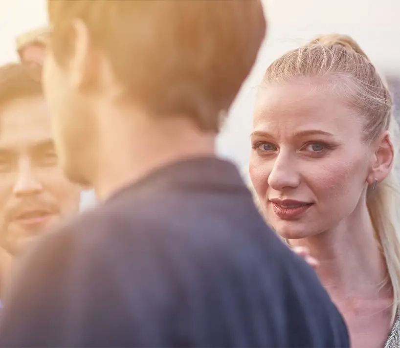 TraumaSolutions A woman with blonde hair looks attentively at a man in the foreground while another man, possibly a trauma therapist specializing in EFT, stands beside them; all are outdoors in natural light.